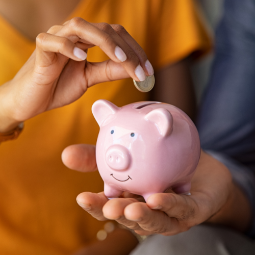 Young couple reviewing their monthly budget together at home, working on a plan to save $10,000 in a year on a tight budget.