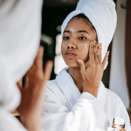woman following skincare routine applying sunscreen.