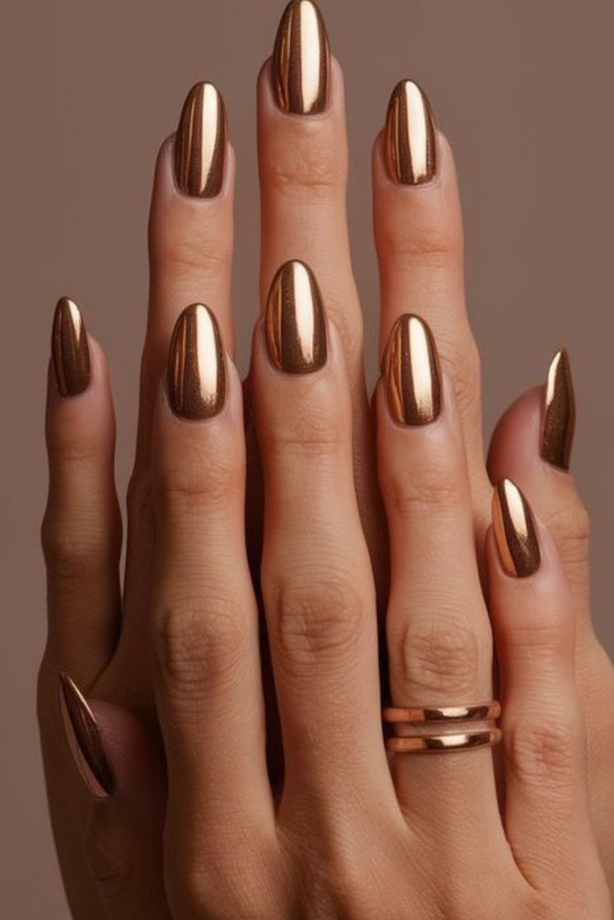 High-shine metallic copper chrome nails reflecting light, perfect for adding a glamorous touch to fall outfits.