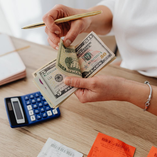 Young woman counting money at a table, symbolizing effective budgeting habits and financial control.