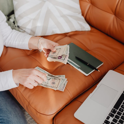Woman holding a stack of cash with pride, illustrating successful money management and budgeting skills.