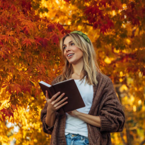Female with her fall bucket list under a tree.