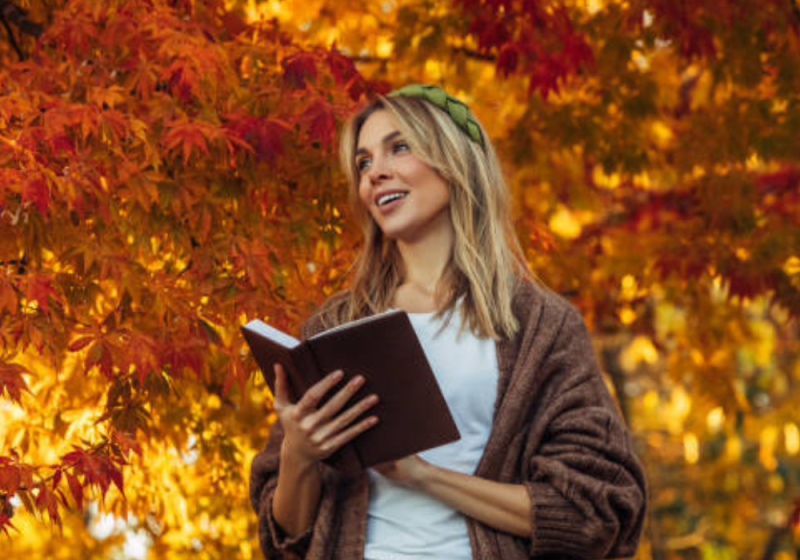 Female with her fall bucket list under a tree.