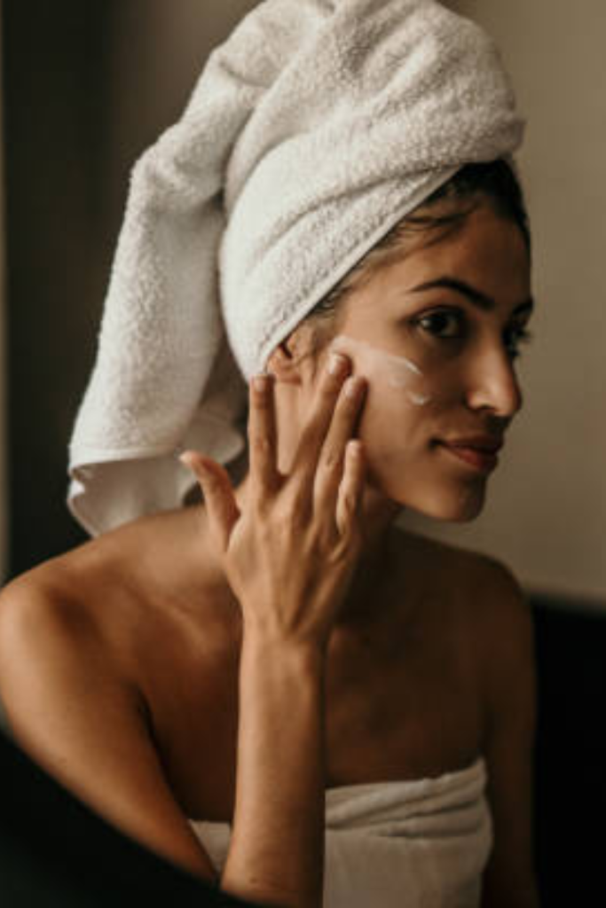 Woman doing skincare routine and checking her reflection in the mirror during fall.