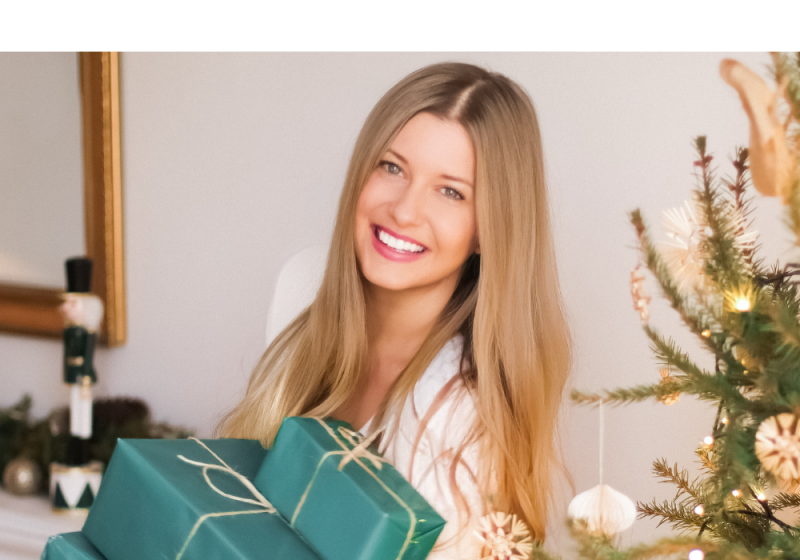 Christmas gifts for her on Christmas day while she is standing next to the Christmas tree.