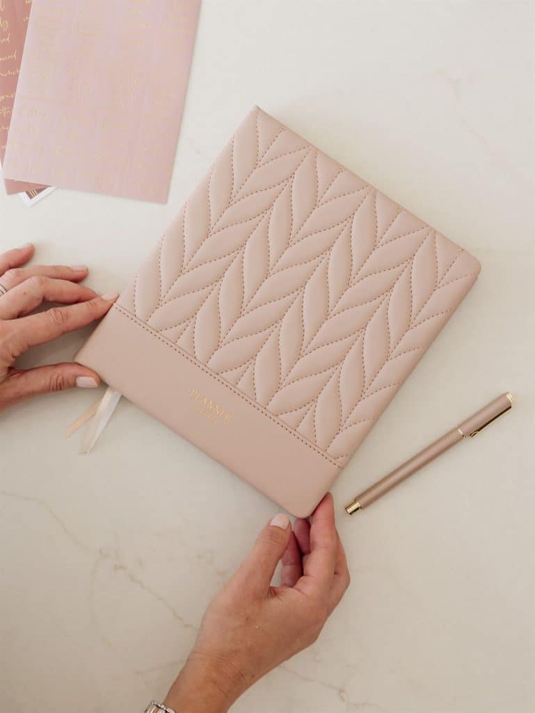 Blush pink quilted LH Agenda planner styled on a neutral desk with matching pen and ribbon bookmarks, highlighting an elegant luxury planning workspace.
